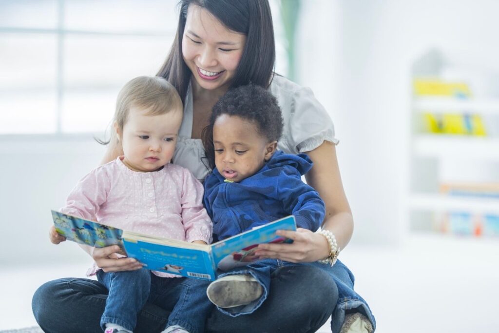 A teacher reading a book with two children