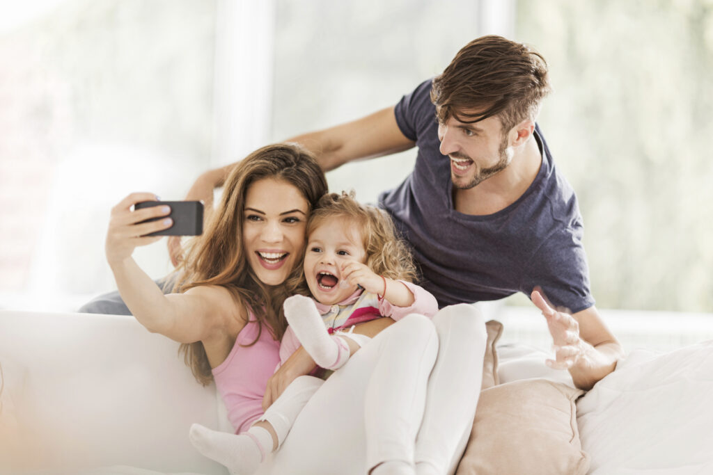 A cheerful family taking a selfie with a cell phone, encouraging positivity.