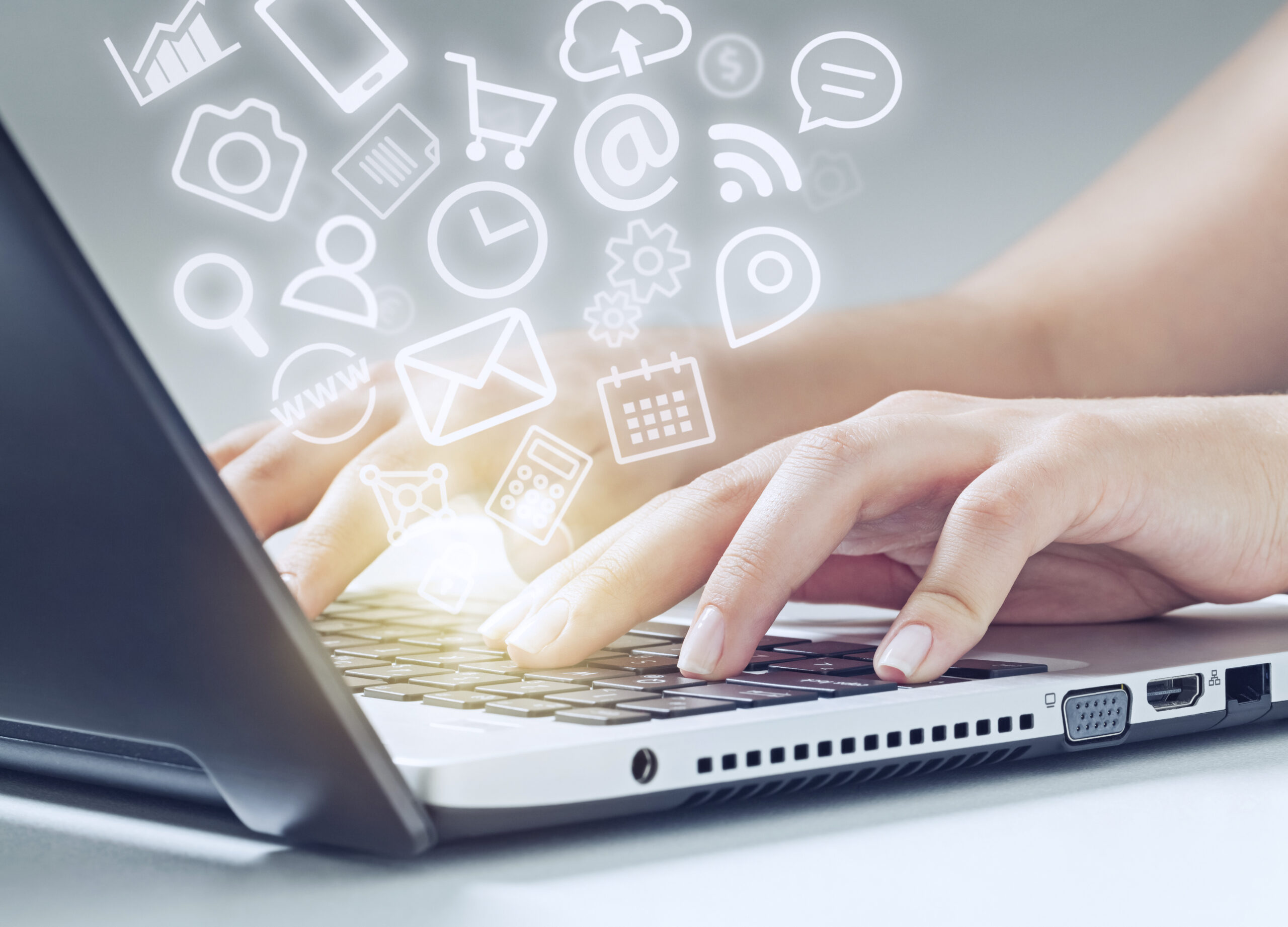 Closeup of a hand typing on a laptop with several icons floating above, representing keeping parents informed as you're dealing with emergency situtations